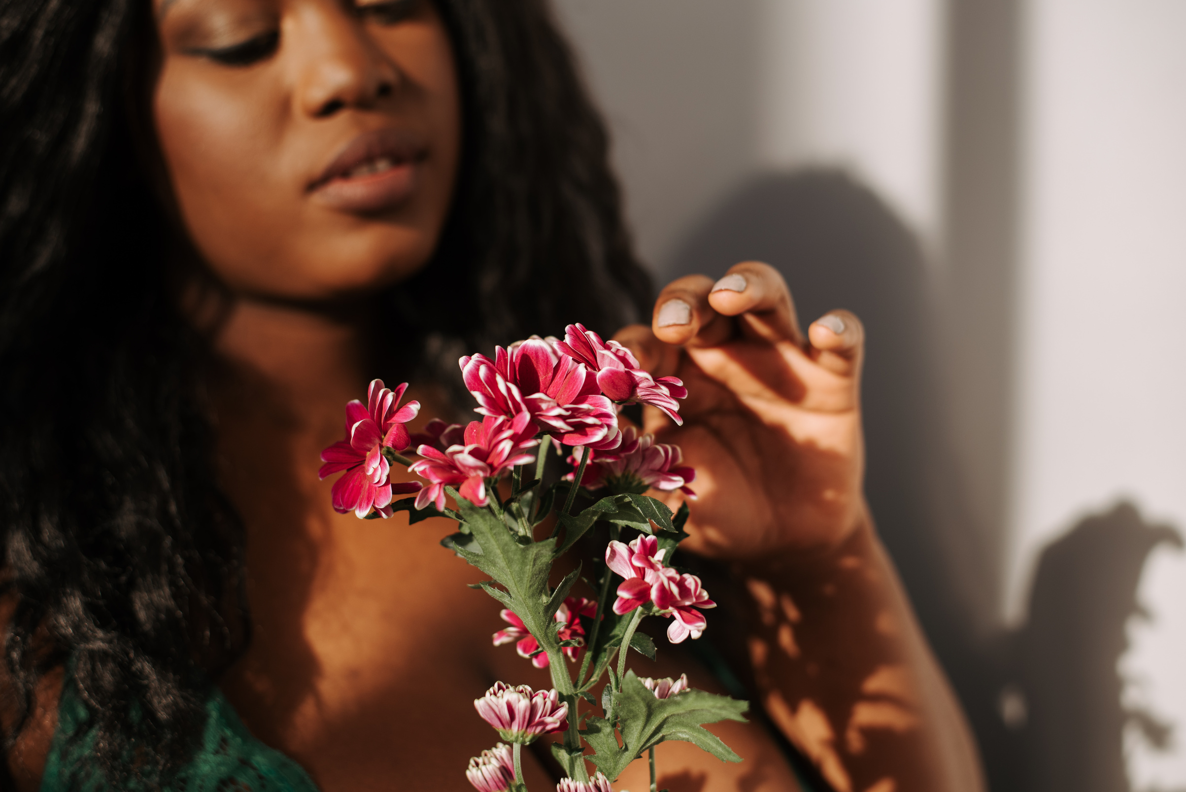 Crop black woman touching blooming flowers in bedroom